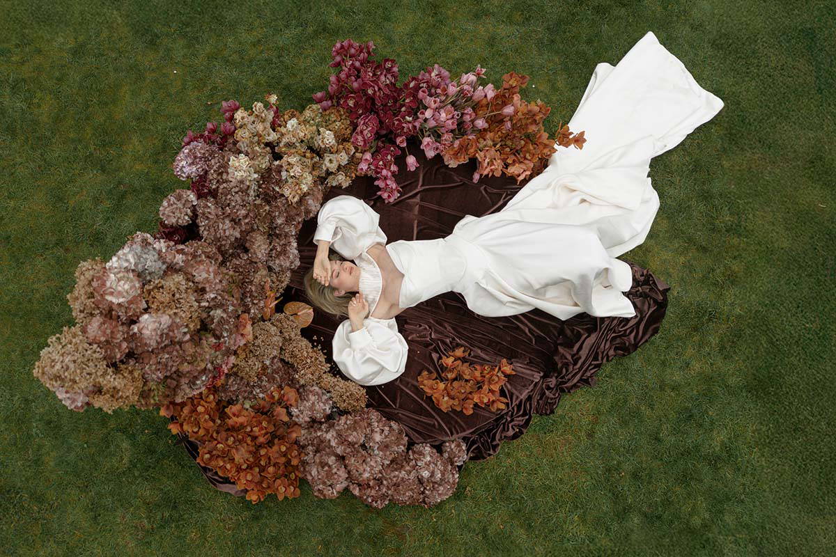 bride lays amongst stunning array of autumnal wedding and events florist manchester